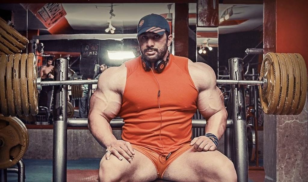 A bulked-up Male Powerlifter on legal-steroids getting ready to bench press weights at they gym.